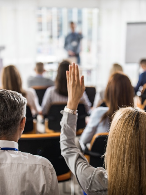 Attendee raises a hand during a conference presentation.